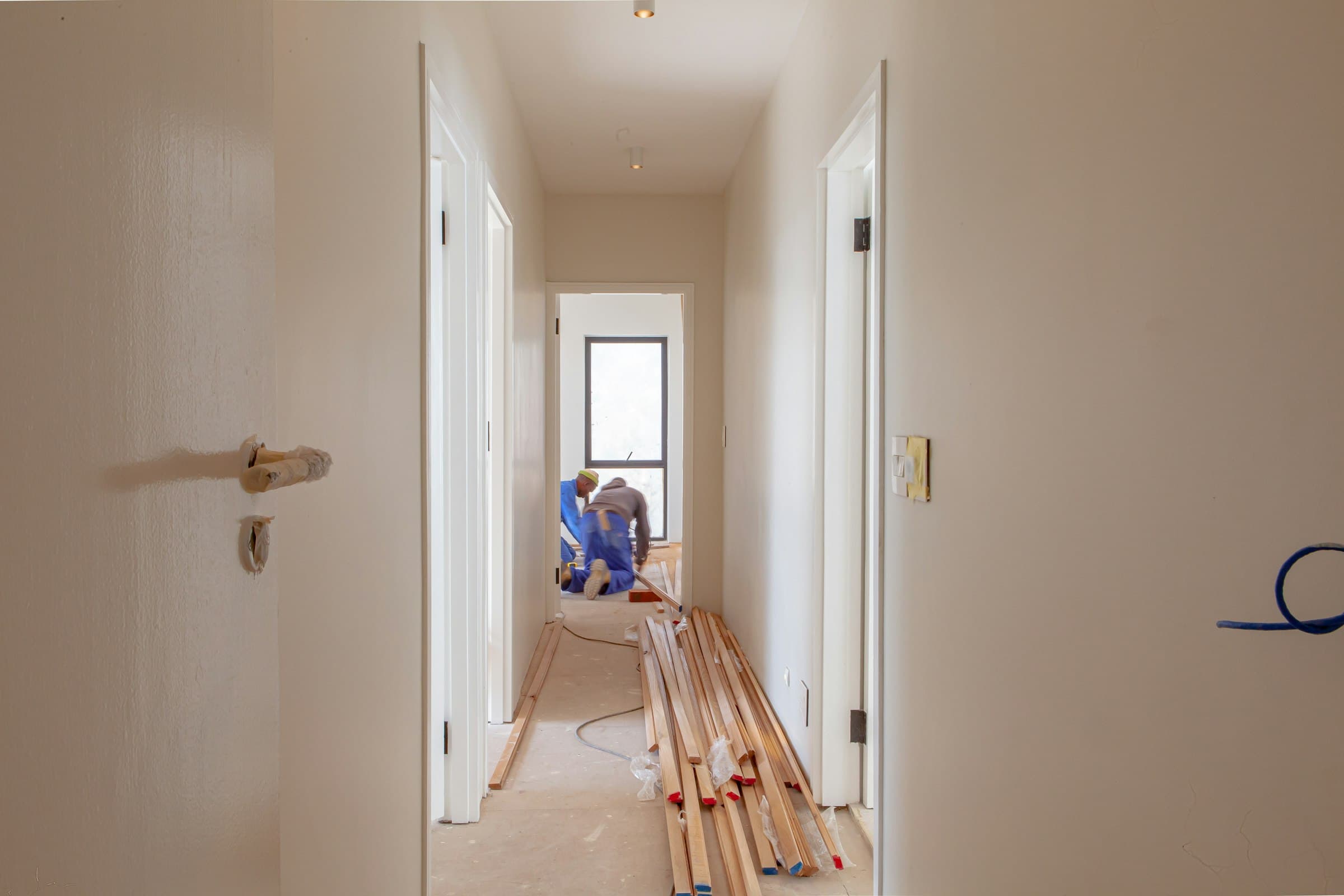 Hantverkare installerar golvlist i en ljus, nyrenoverad hall.